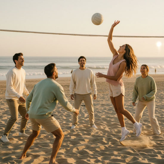 Group of people playing volleyball on a sandy beach at sunset.