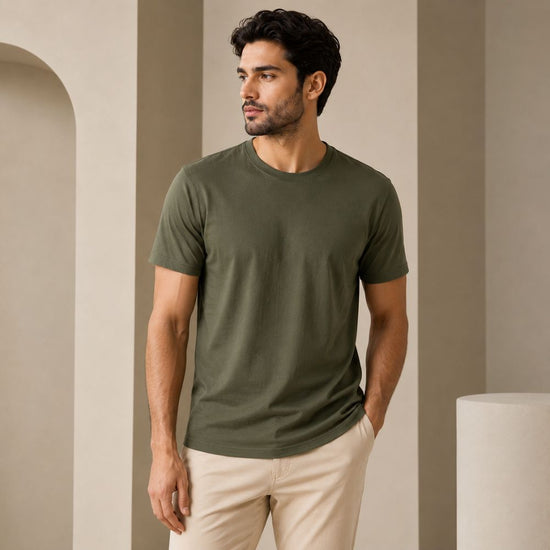 Man wearing a green t-shirt and beige pants against a neutral background